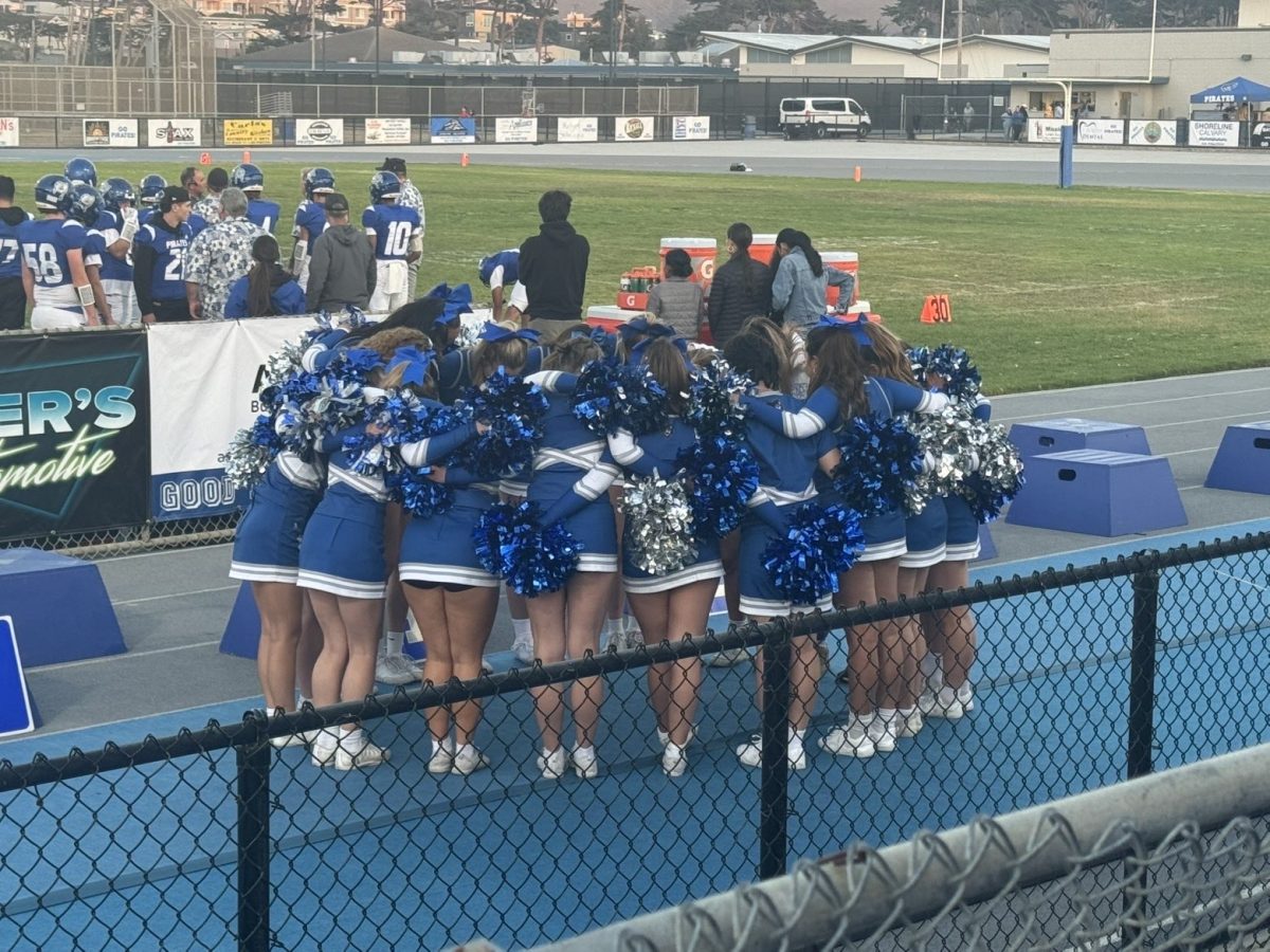 Picture of the varsity cheer team in a huddle during one of the football game.  
