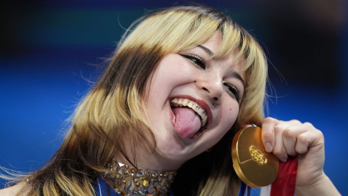 Alysa Liu striking her tongue out while posing with her Olympic gold medal. 